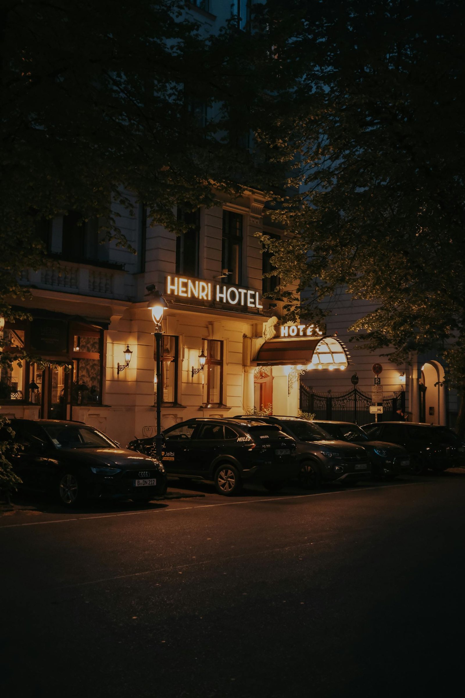 Exterior of Henri Hotel Berlin during night with parked cars and street lights.